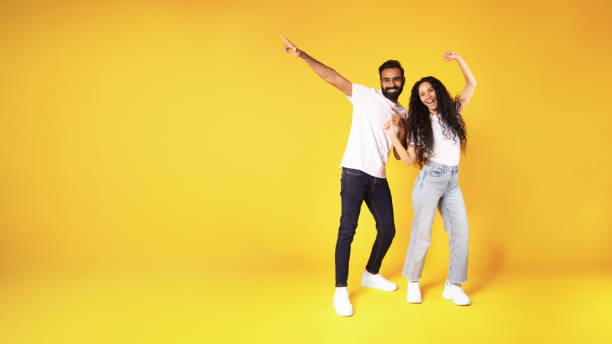 istock Middle eastern couple pointing finger at copy space, yellow background 1777266687
