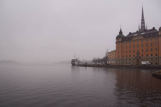 View of buildings by river against cloudy sky