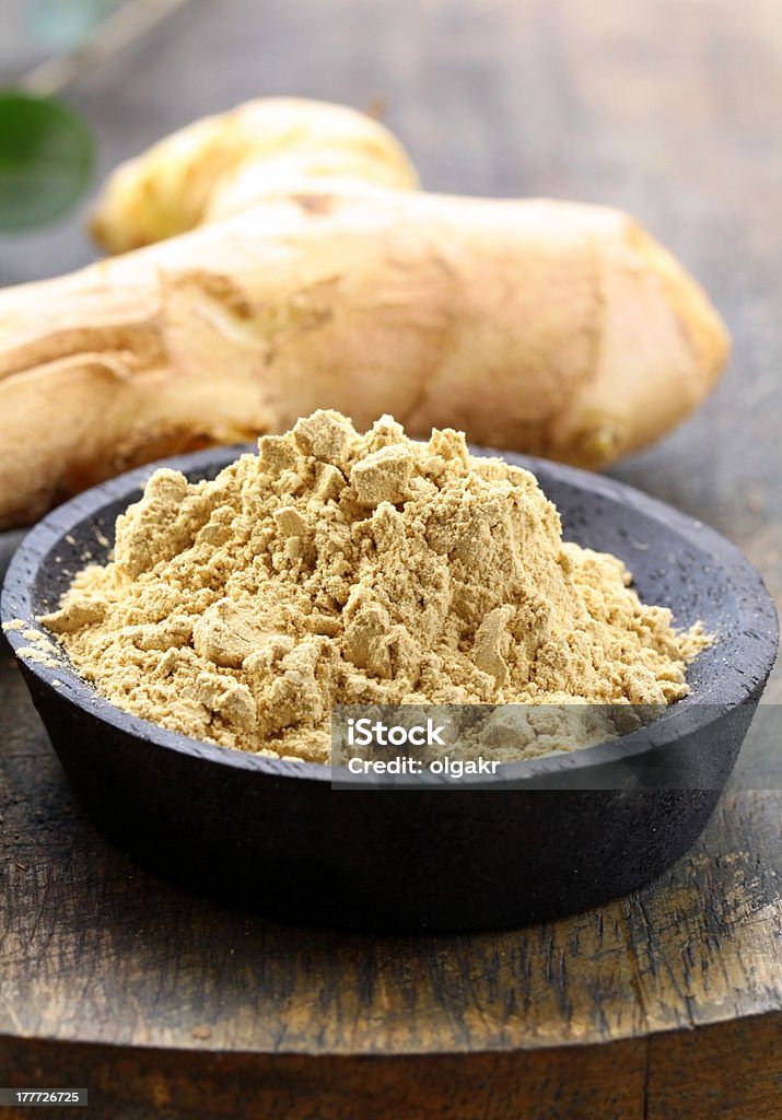 ground ginger (spice) and fresh on a wooden board Bowl Stock Photo