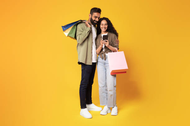 istock Middle Eastern Spouses Using Mobile Phone Shopping On Yellow Background 1777277433