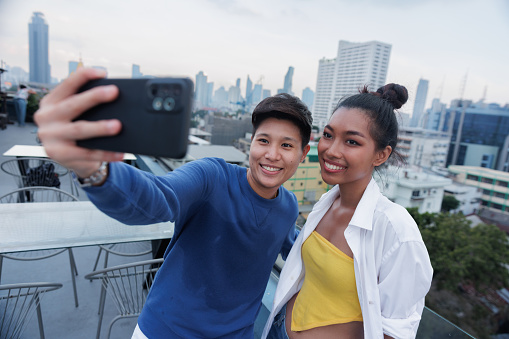 LGBT couple using smart phone selfie on rooftop