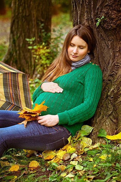 pregnant woman relaxing in the park stock photo