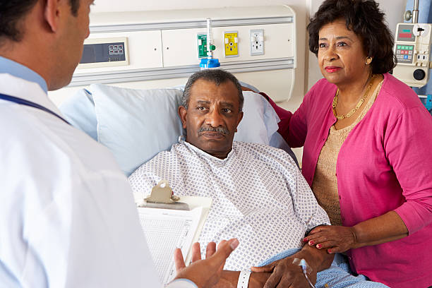 médecin parlant à couple senior sur ward - patient doctor african descent hospital photos et images de collection