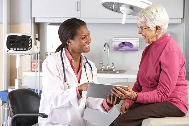 A doctor confronts a smiling senior with good news Doctor Discussing Records With Senior Female Patient Smiling general practitioner photos stock pictures, royalty-free photos & images