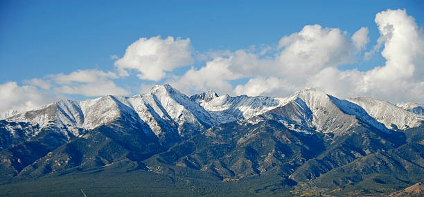 istock Snow-capped mountain peaks with puffy clouds and blue sky 177732134