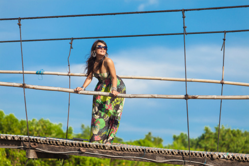 Young asian woman in floral dress suspension bridge in tropical Bali