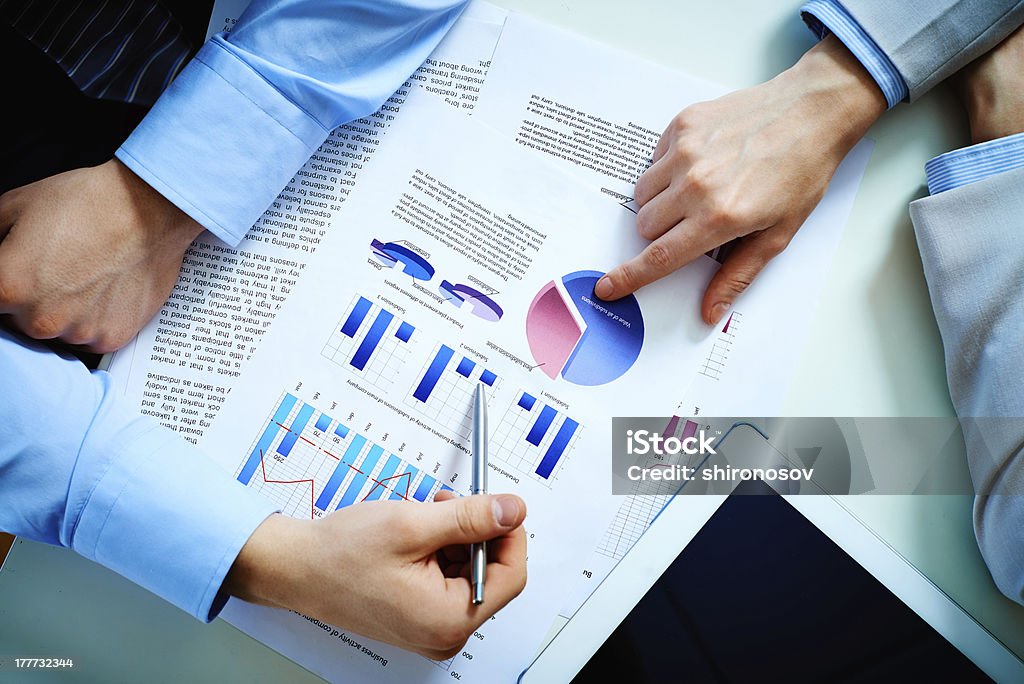 Two businessmen discussing a colorful info graph Close-up of female and male hands pointing at business document while discussing it Arranging Stock Photo