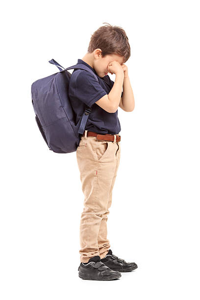 Full length portrait of a schoolboy crying Full length portrait of a schoolboy crying, isolated on white background sad child standing stock pictures, royalty-free photos & images