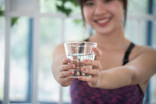 Woman drinking water hands holding cold mineral water cool drinking. Asian women smile laugh look away health care home fitness lifestyle. Cheerful Beautiful female drink glass of water smile face