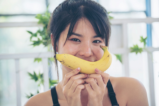 Banana Healthy eating young woman workout holding organic banana fruit healthy lifestyle. Wellness Asian women use yellow banana smile face look at camera. Beautiful healthcare nutrition lifestyle