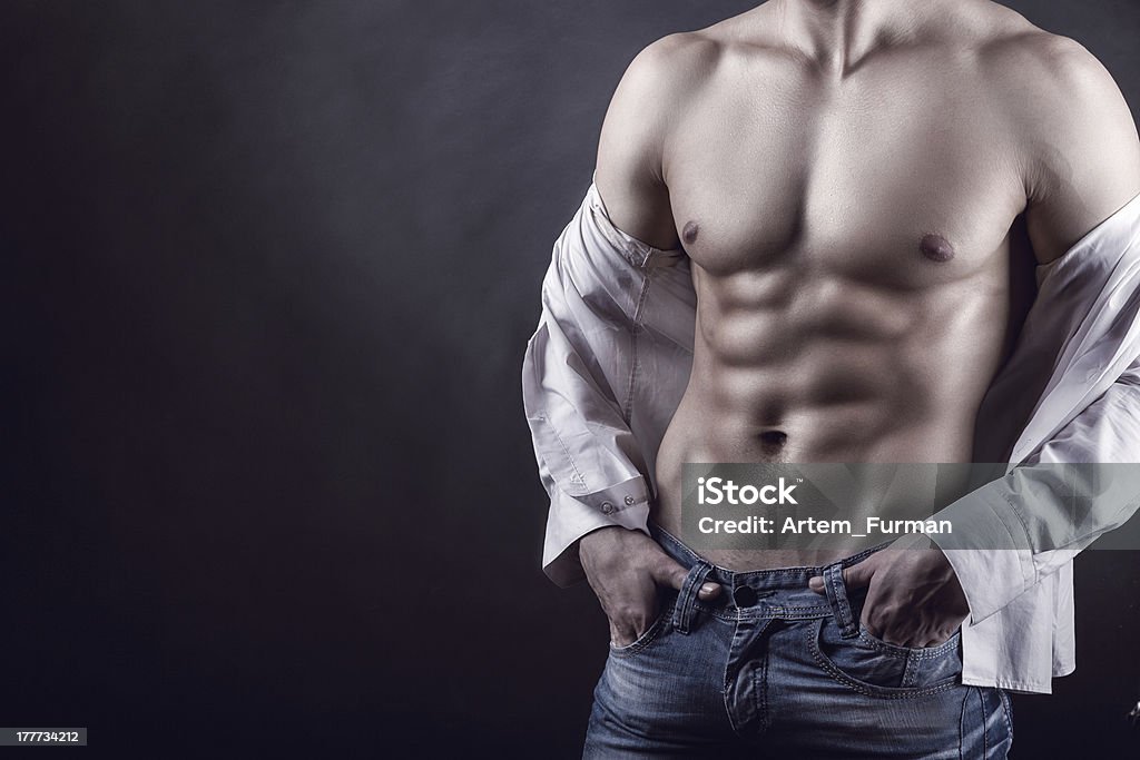 Sexy man Sexy young man in a shirt with a naked torso on a dark background Abdomen Stock Photo