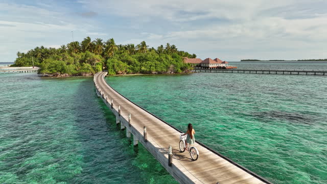 Beautiful woman riding bicycle on wooden jetty