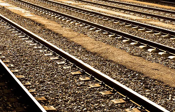 Railways sleepers and stones with bright of the Sun on the rails perspective.