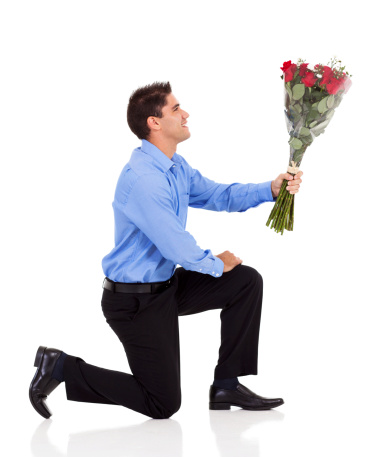young man knee down on floor and giving bunch of roses isolated on white