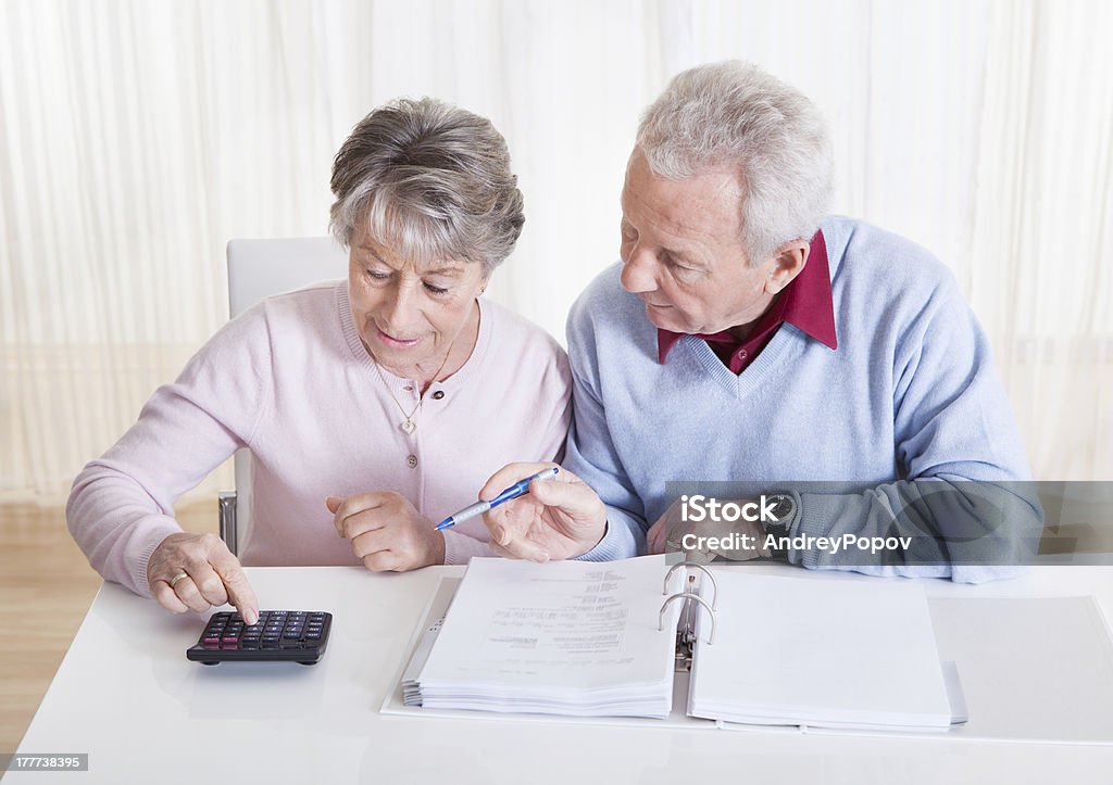 Senior Couple Calculating Budget Photo of Senior Couple Calculating Budget At Home Accounting Ledger Stock Photo