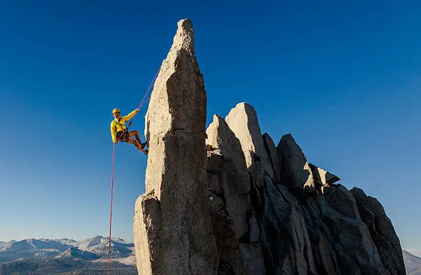 Climber wearing a helmet rappels from the summit during a challenging and successful ascent in Yosemite National Park.