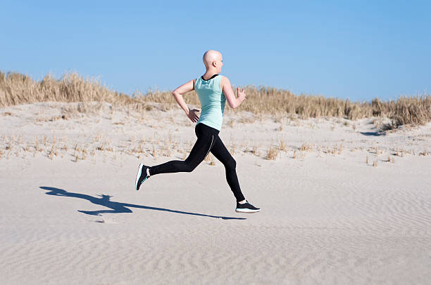 jovem mulher com bald head jogging após quimioterapia - secondary action imagens e fotografias de stock