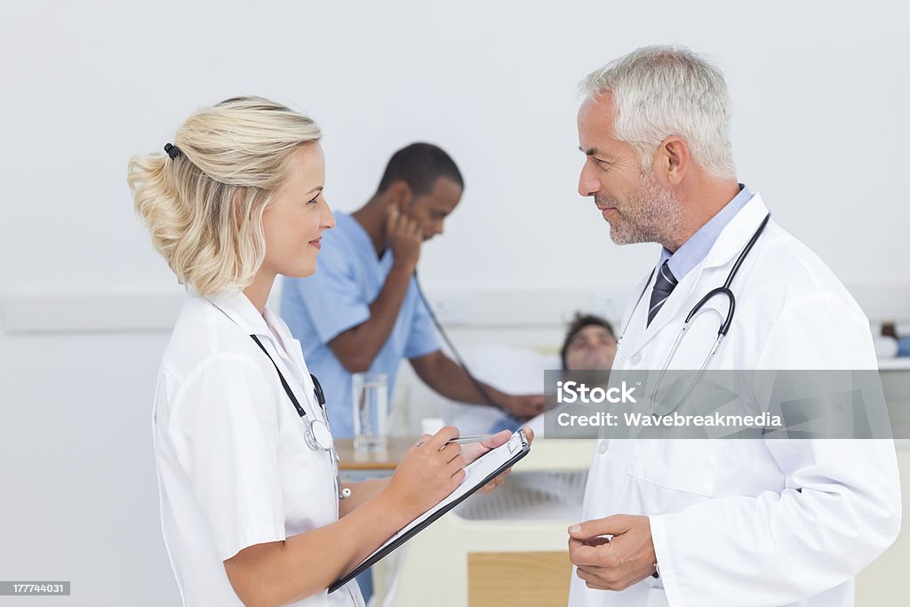 Doctors talking together Doctors talking together in front of the patient 20-29 Years Stock Photo