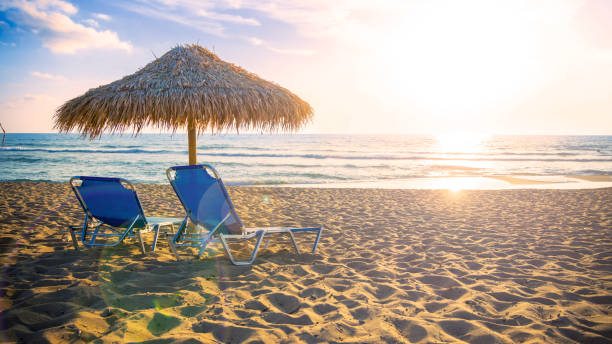 istock Two Chaise lounges under umbrella on the beach at sunset 1777450608