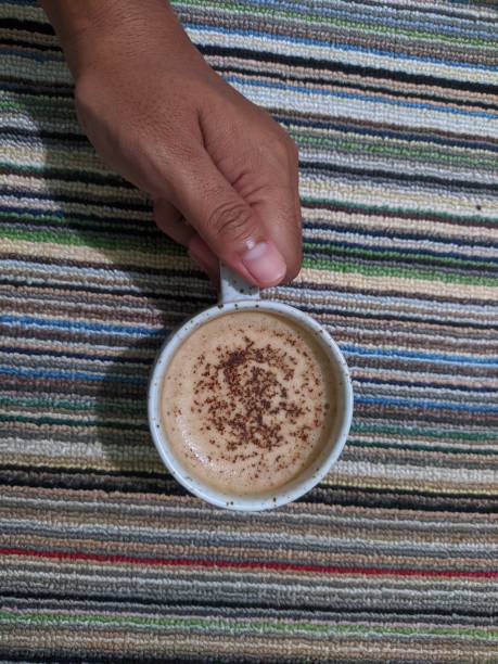 A man's hand is holding a white coffee cup