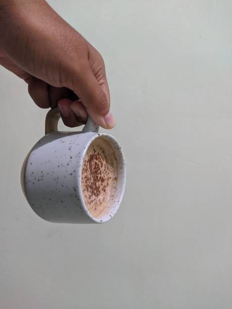 A man's hand is holding a white coffee cup