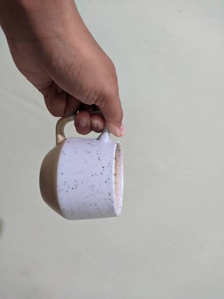 A man's hand is holding a white coffee cup