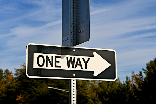 A “one way” sign warns drivers at an intersection that the road is only one direction.