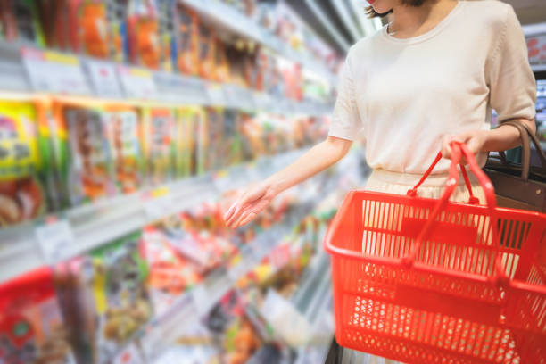 Asian woman consumer choosing asia food product at supermarket store Consumer shopping at supermarket concept. Young adult asian woman customer choosing instant asia food product from shelf. Consumer buying at grocery store lifestyles. taiwan people stock pictures, royalty-free photos & images