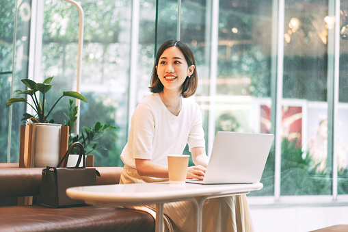 Asian woman using laptop and waiting at coffee cafe city break weekend balance lifestyle