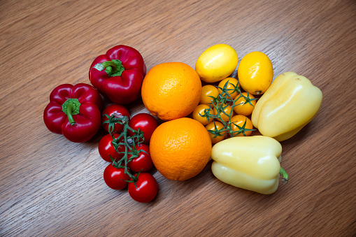 A wooden cutting board showcases a colorful assortment of orange, red, and yellow fruits and vegetables, ready to be prepared for a delicious meal.