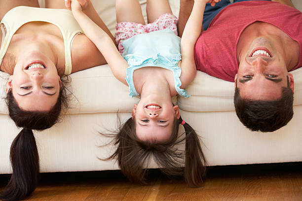 familie liegen auf den kopf auf sofa mit tochter - women group of people lying down mother stock-fotos und bilder