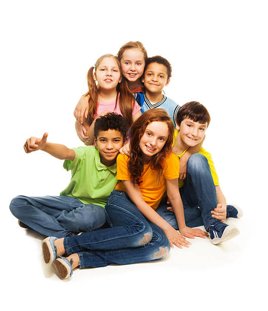 Portrait of beautiful children, boys and girls in stylish vintage clothes sitting, looking at camera isolated on white background. Concept of childhood, friendship, lifestyle, fashion. Retro style