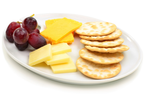 Cheese and crackers with grapes on oval white plate