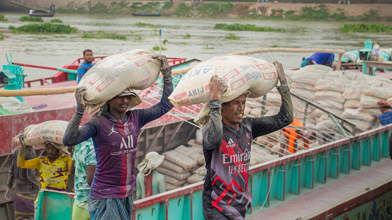 Day laborer unloading cement from the boat, This image was captured on May 29, 2022, from Amen Bazar, Bangladesh