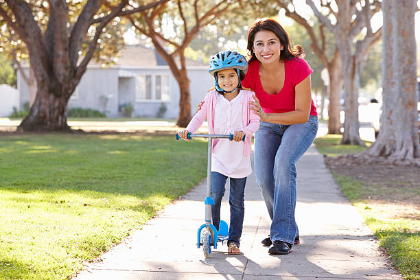 istock Mother Teaching Daughter To Ride Scooter 177750174