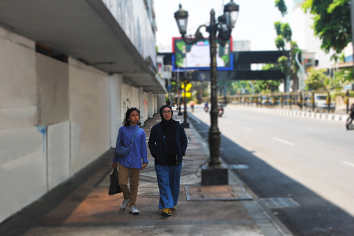 Two Asian women are walking in the downtown street.