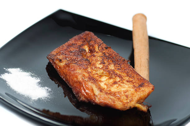 French toast, torrijas, and cinnamon stick on a black plate stock photo