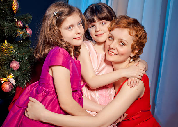 Mother and daughters near Christmas tree stock photo
