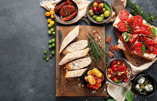 Italian antipasti snacks set. Tasty bruschettas with cheese, sun-dried tomatoes. Traditional food concept. Top view, copy space.