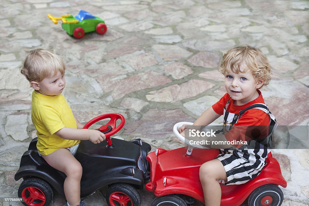 Two little brothers toddlers playing with cars Two little brother toddlers playing with toy car in summer garden Bobby-Car Stock Photo