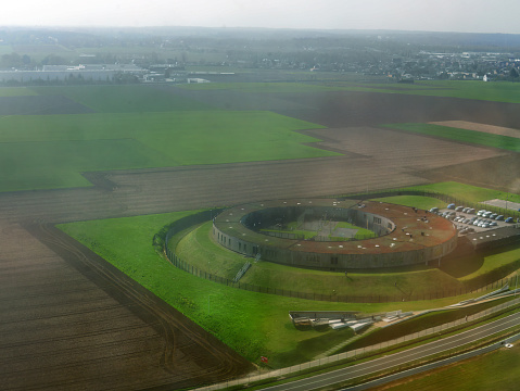 Aerial view from airplane seeing large round circle shape building, architecture design, on green area, view from above