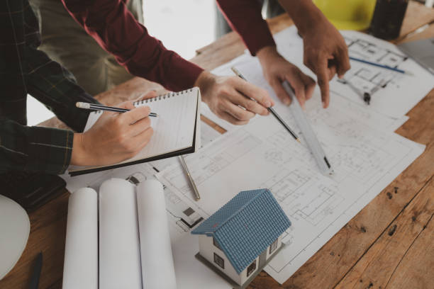 istock Architects and engineers work together to come up with solutions to house building problems, The property is about to be designed by a group of engineers, Architects are reviewing plans together. 1777558849