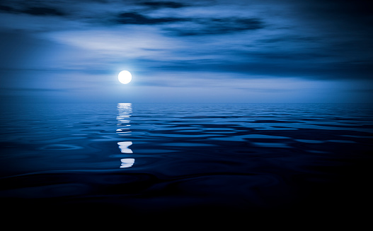 The blue moon hung over the surface of the calm ocean.