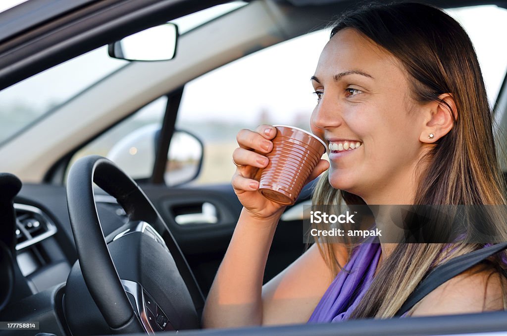 Donna felice godersi un drink mentre sei in viaggio - Foto stock royalty-free di Automobile