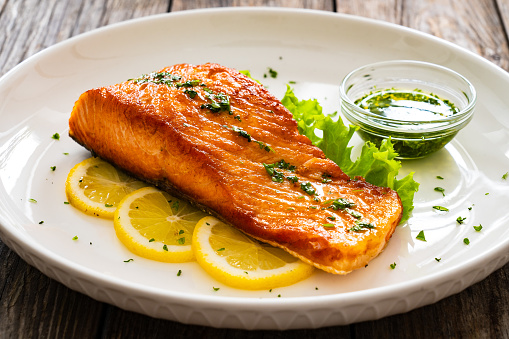 Seared salmon with fresh vegetables on wooden table