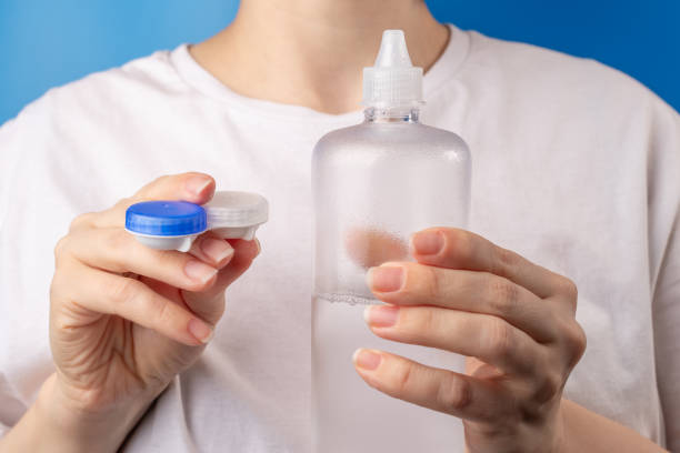 istock Liquid solution for eye lenses, woman holding cleansing and moisturizing bottle and contact lens case on blue background 1777595245