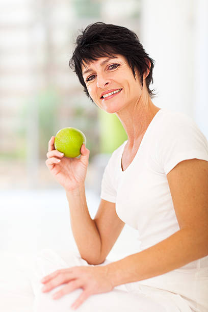 istock mature woman holding a fresh green apple 177761886