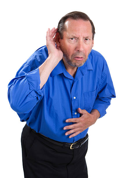 Senior Hearing Loss Senile senior adult male cups his hand to the ear because of a loss of hearing problem. old man cupping his ear to hear something stock pictures, royalty-free photos & images