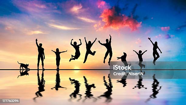 Happy Friends Family With Dog And Cat Jumping At Sunset Stock Photo - Download Image Now