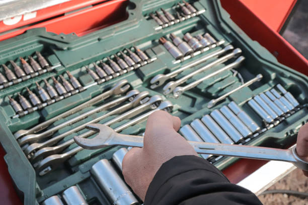man holding an fixed wrench next to the tool cart